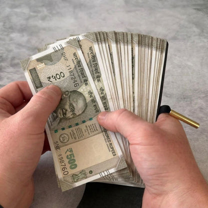 Hands holding a stack of Indian currency notes on a neutral background
