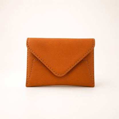 A small envelope-style card holder wallet in warm cognac brown faux leather, shown on a clean white background.