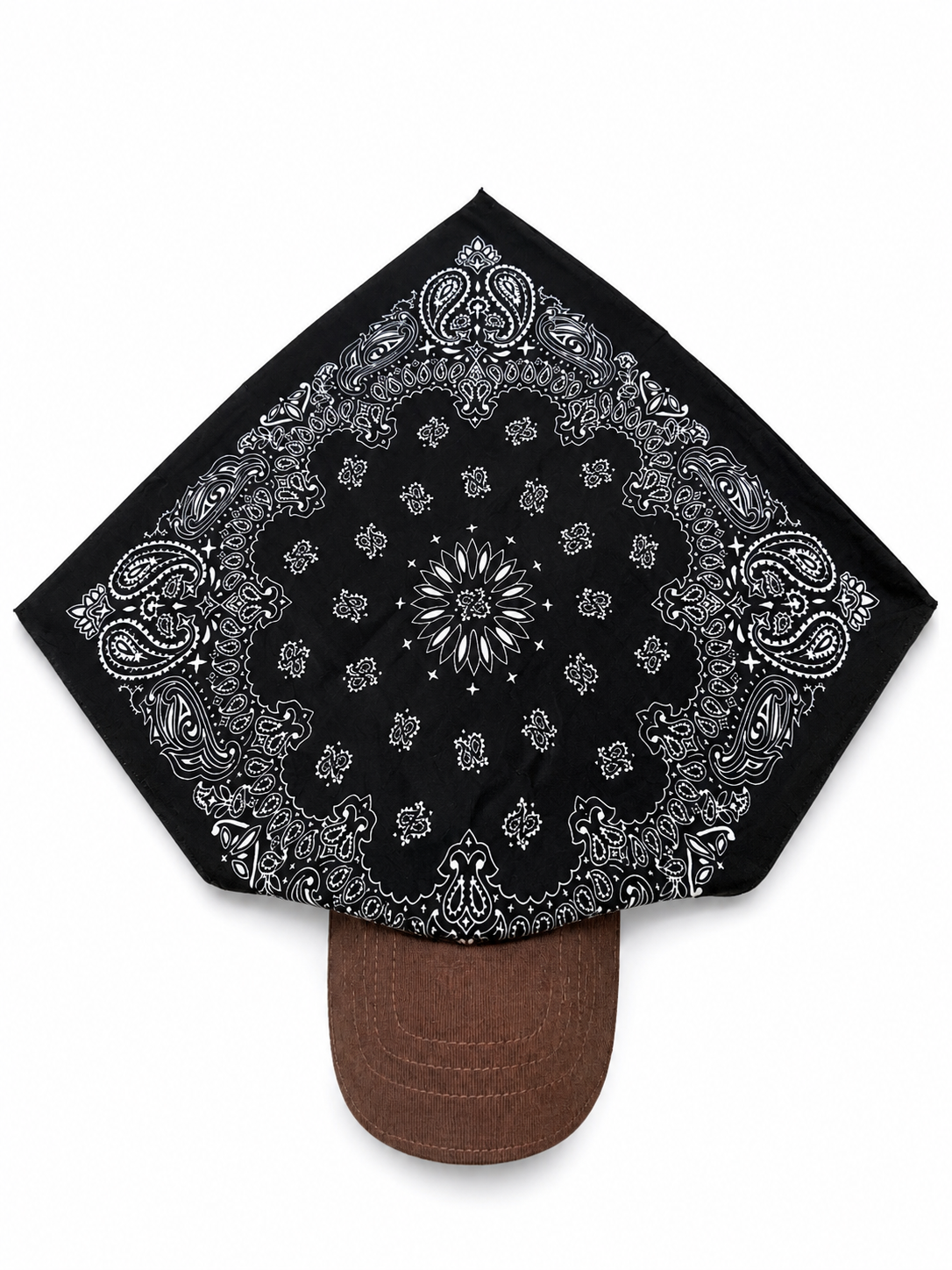 A black bandana with a white paisley and floral pattern, draped over the crown of a brown baseball cap against a plain white background.