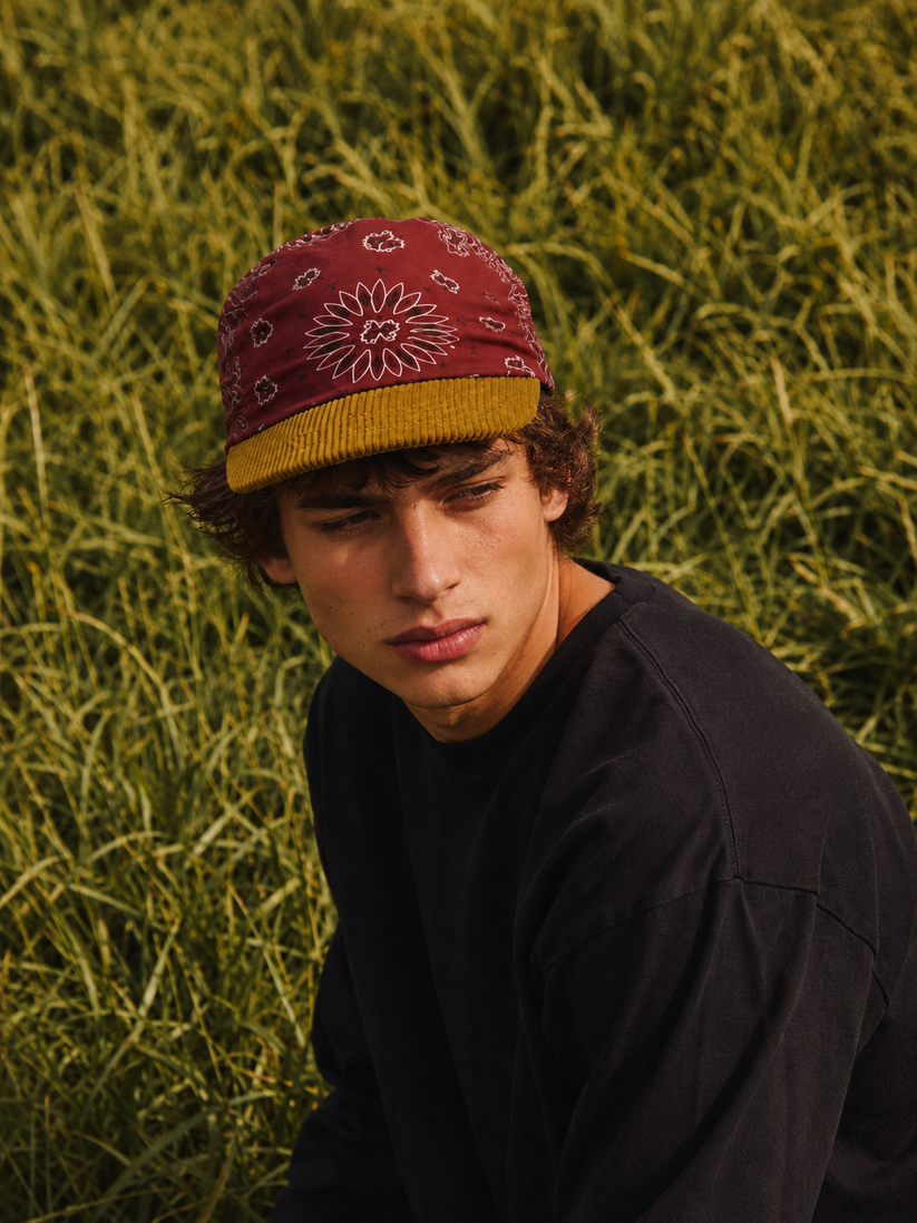 Person wearing a red bandana cap and black shirt against a green grass background