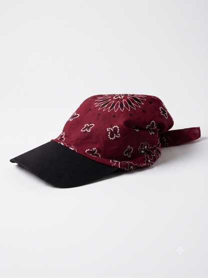 A baseball cap featuring a burgundy bandana print crown and a solid black curved brim, photographed on a clean white studio background.