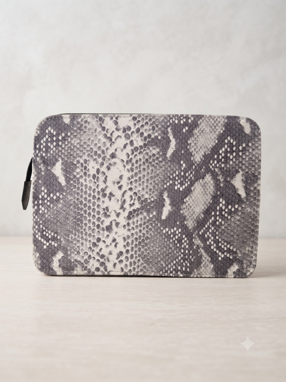 A zippered pouch featuring a gray and white snakeskin pattern, displayed on a light beige surface against a neutral gray background.