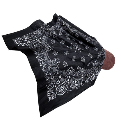 A black bandana with a white paisley and floral print, draped over a brown mannequin head against a plain white background.