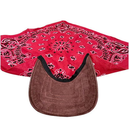 A red paisley bandana with black and white detailing, laid out behind a brown corduroy cap with a black trim, on a plain white background.